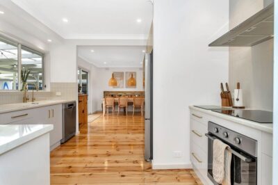 Port Noarlunga South kitchen renovation Renovated kitchen with white cabinetry and brass handles opening to the dining area