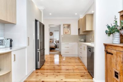 Port Noarlunga South kitchen renovation with restored hardwood floors Renovated kitchen with white cabinetry and resanded polished hardwood flooring